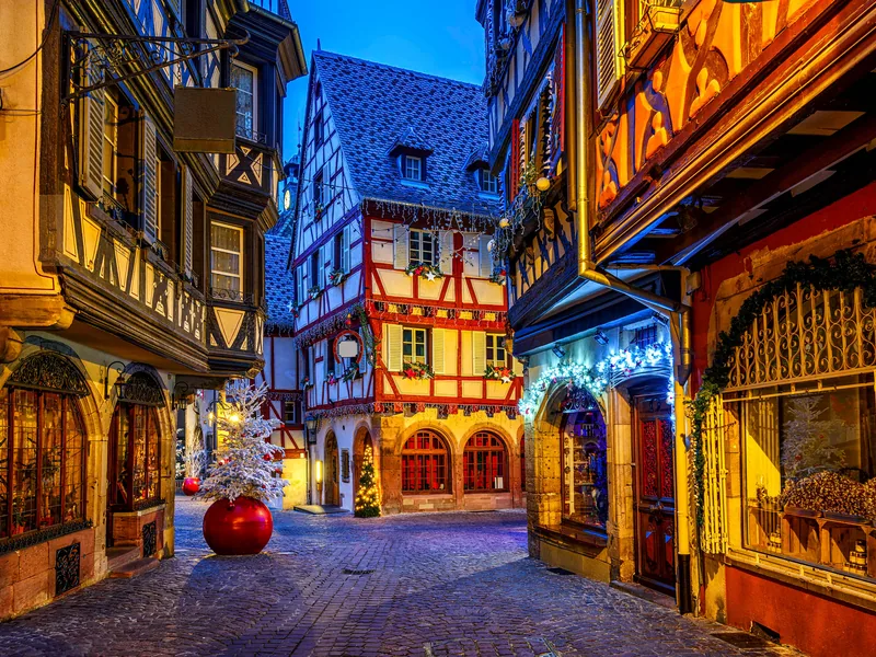 Rue des Marchands in Colmar at dusk, lit shopfronts and Christmas decorations